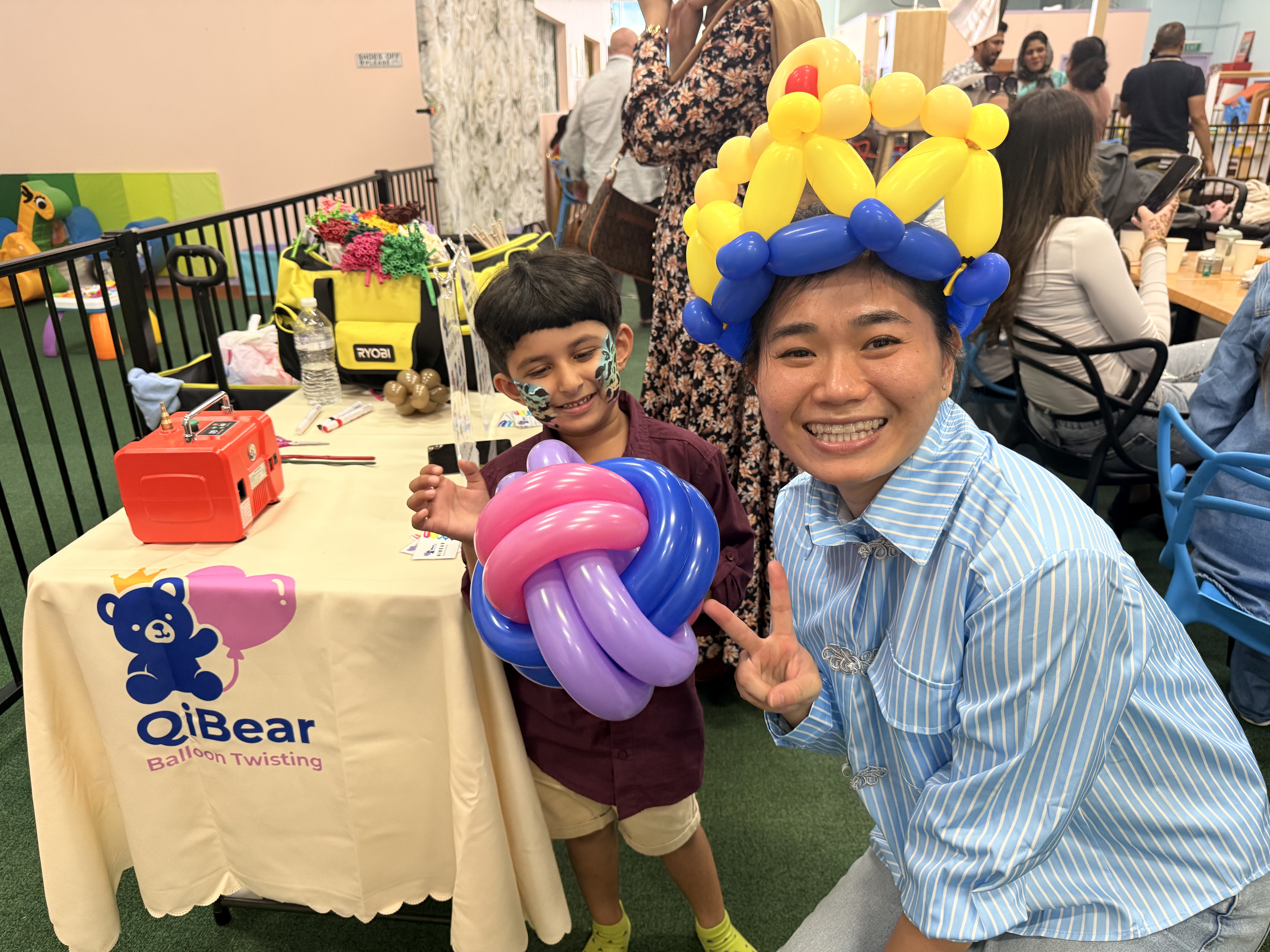 Balloon artist posing with boy holding knot balloon