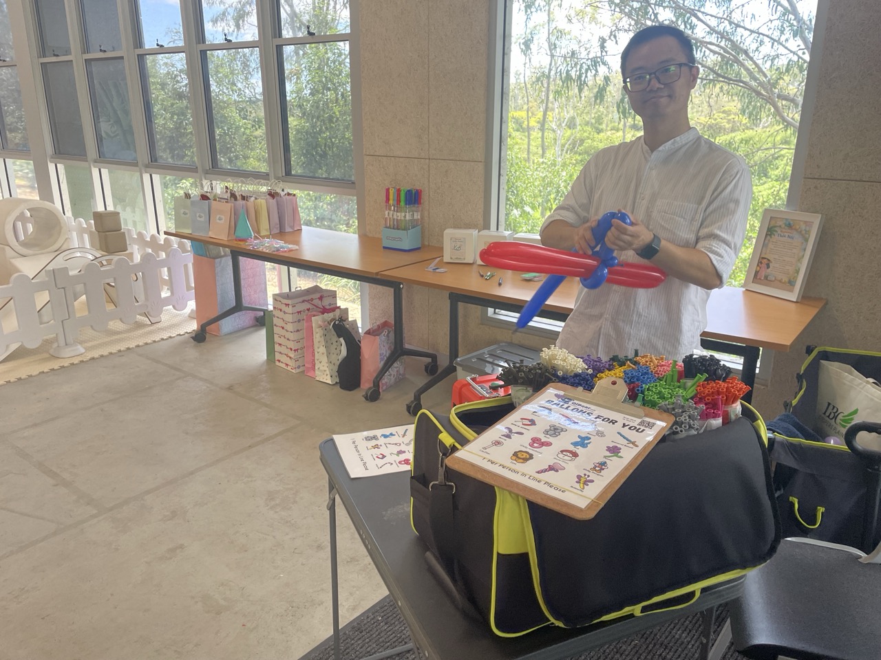 Balloon artist setting up display with a red dog balloon